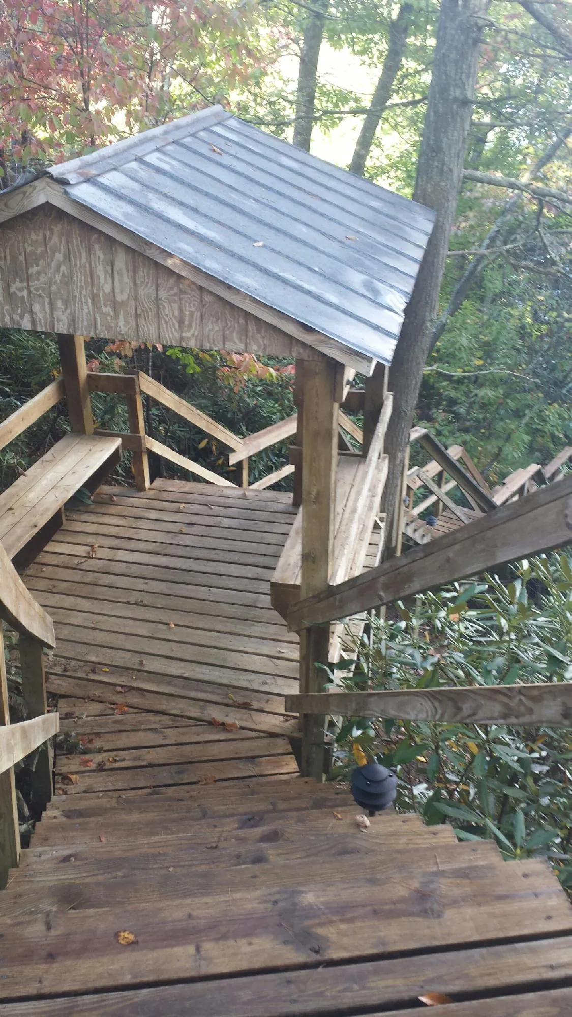 Metal roofed shelter over wooden steps on a wooded walkway — Skylight Repair & Installation work by our crew in Millville